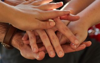 Des mains qui s'empilent les unes sur les autres pour symboliser la solidarité de cette nouvelle newsletter de la ligue, à 4 voix. Un pour tous et tous pour vous ! Image Canva